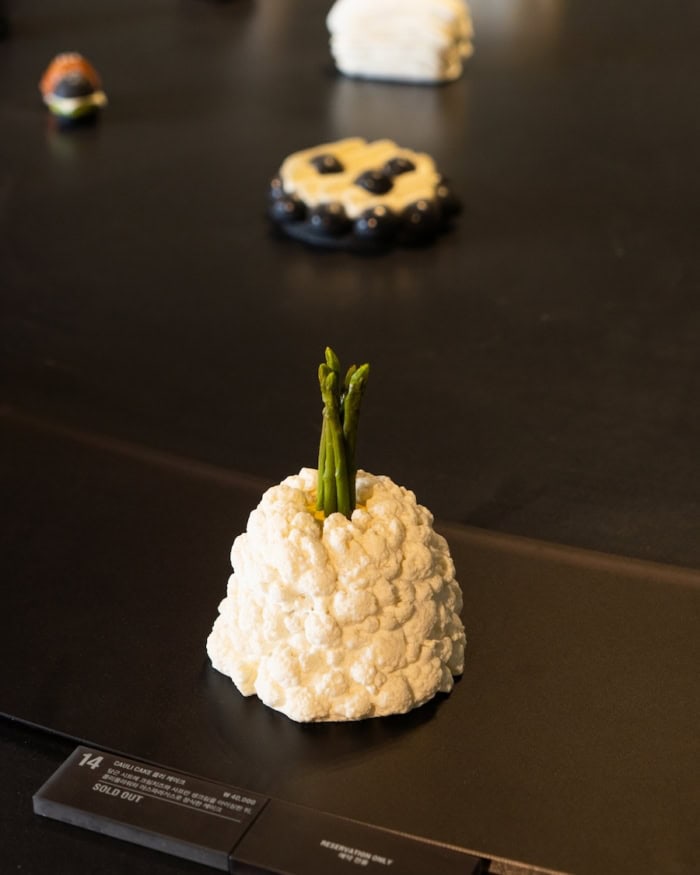 Nudake cauliflower with asparagus White cake that's shaped like a cauliflower with asparagus popping up in the center