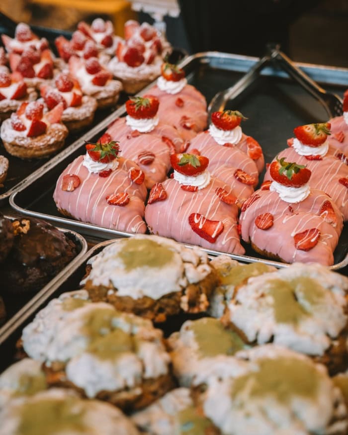 sweet croissants Trays on a table of three different types of dessert. Two have strawberries decorating them and one is topped with a green matcha powder.