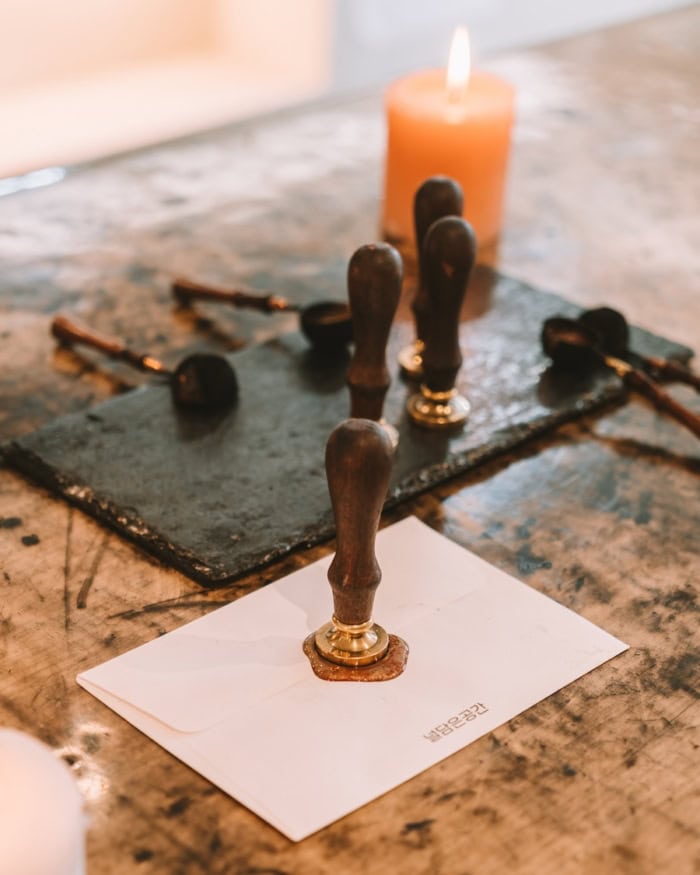Nuldam Space letters Table with an envelope on it and a wax seal pressing into the envelope.