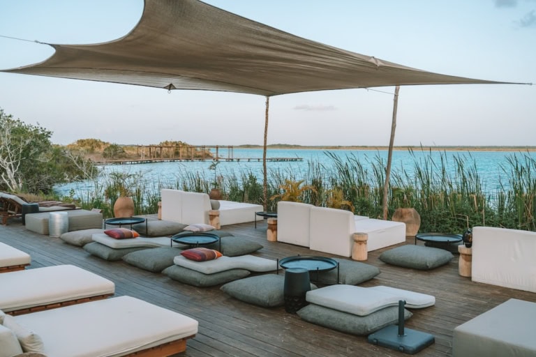 Sun deck at Habitas Bacalar with sun bathing chairs and the turquoise lagoon in the distance