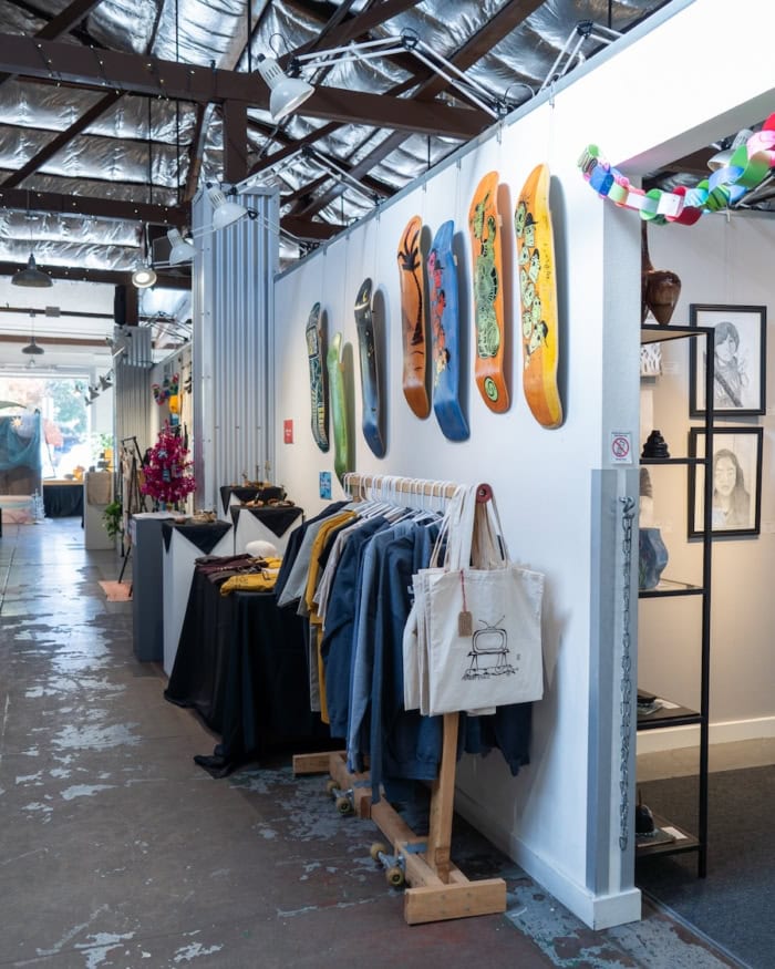 Studios in the Park Interior of an art studio in Paso Robles where there are a rack of clothes and colorful painted skate boards that line the wall.