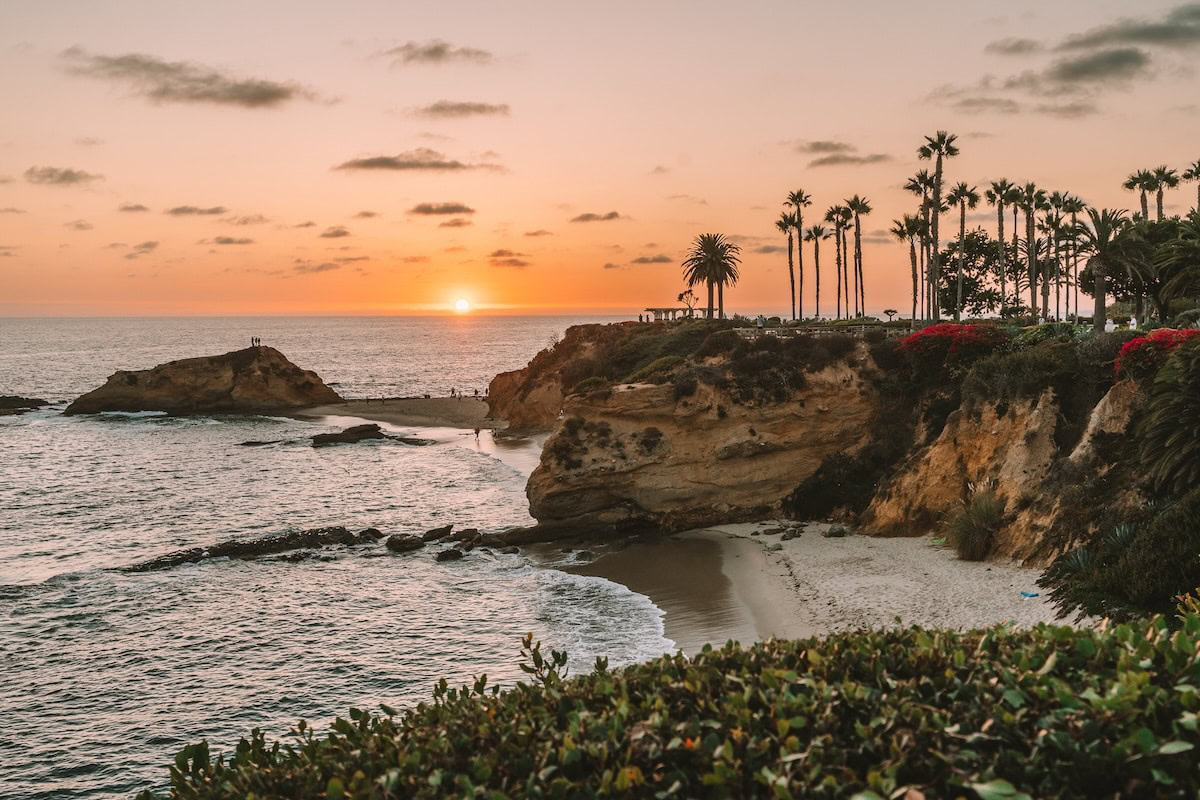 Treasure Island beach Sunset overlooking a cove at Treasure Island beach with tall cliffs and palm trees above the sand.