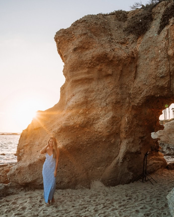 sunset Treasure Island Beach Michelle Halpern standing in front of a rock formation with a cave at Treasure Island Beach
