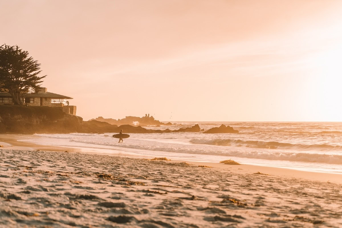 Carmel Beach at sunset Surfer getting ready to enter the ocean at Carmel Beach at sunset