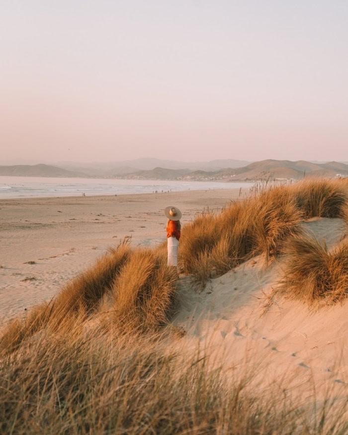 sand dunes at Morro Rock Beach Michelle Halpern standing in a red sweater on the sand dunes at Morro Rock Beach.