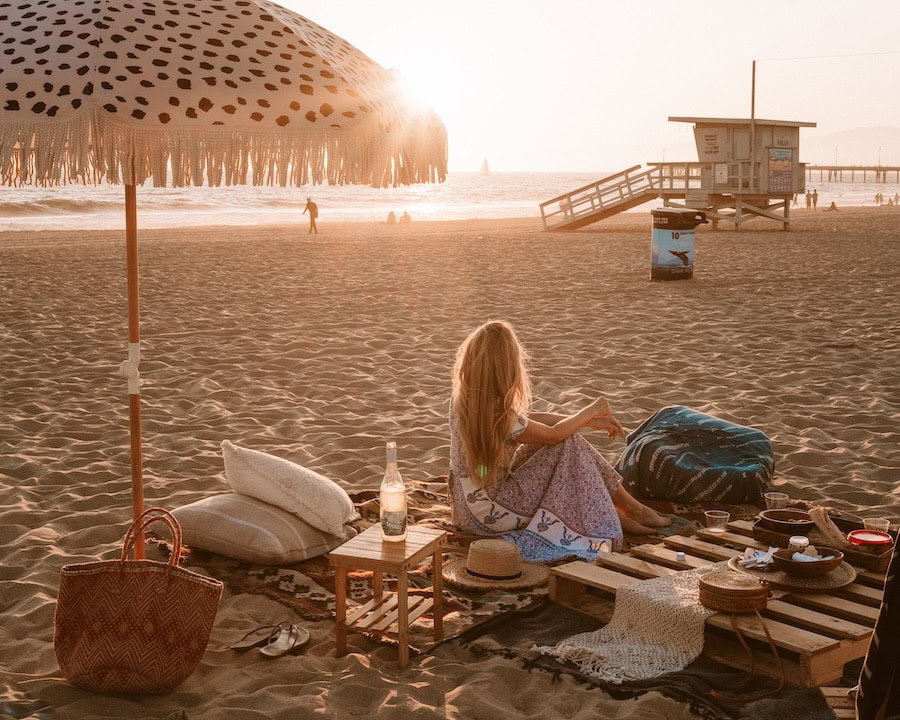 ifeguard stand Michelle Halpern sitting on a beach picnic setup looking out onto an iconic lifeguard stand at Venice Beach