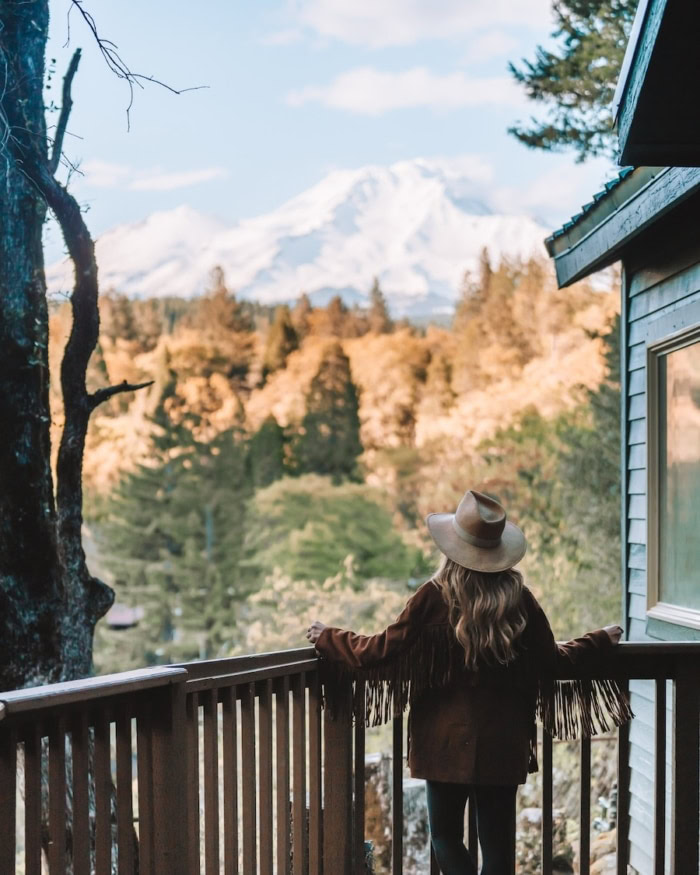 Cave Springs Resort patio Michelle Halpern standing on patio of tiny home at Cave Springs Resort looking out on Mount Shasta