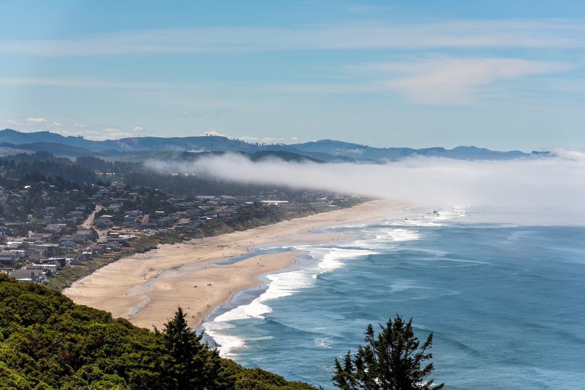 Best Oregon Coast Towns Coastline of Lincoln City, Oregon from above with low lying clouds hanging over the beach.