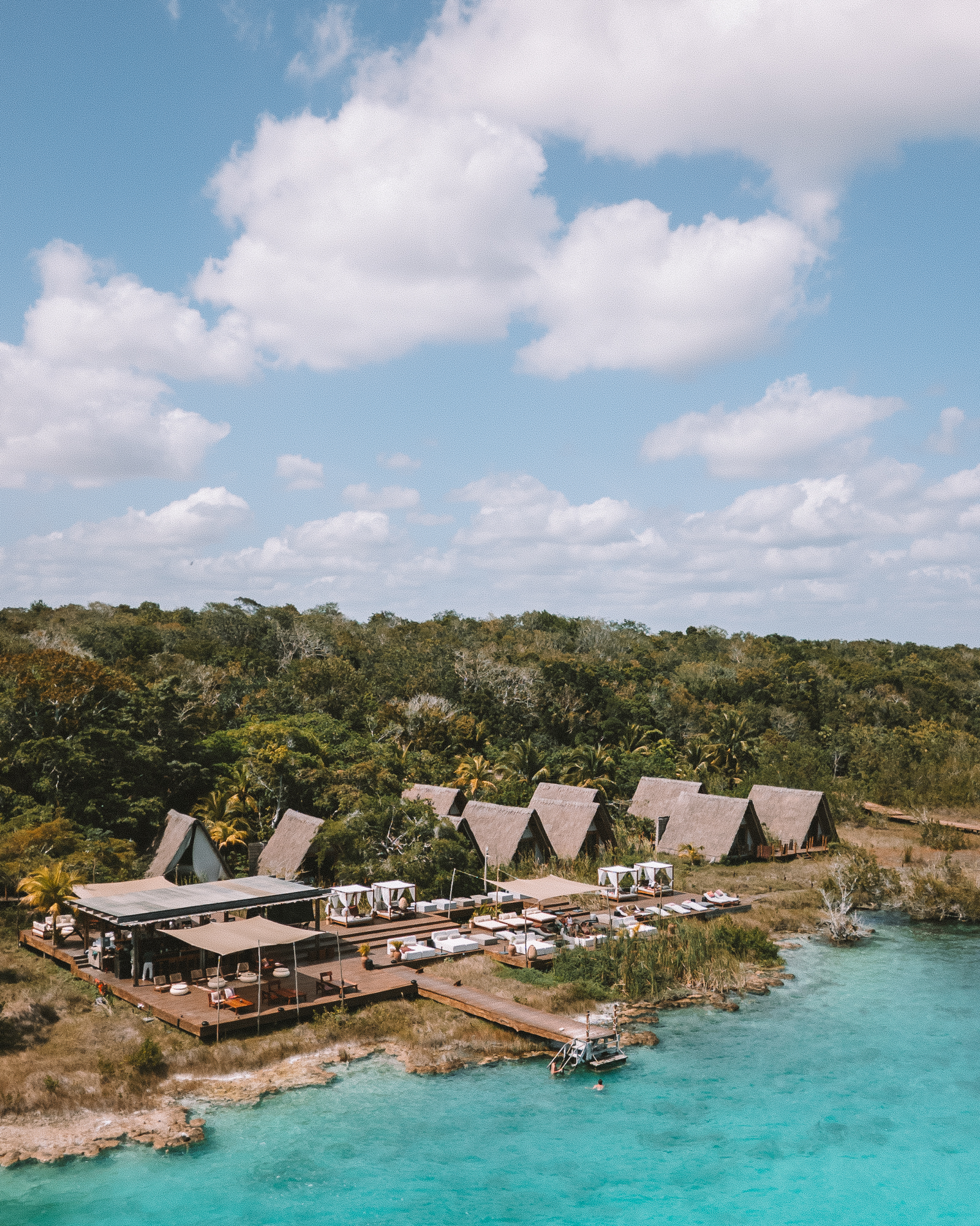 Thatched bungalows looking out onto a turquoise lagoon at Habitas Bacalar