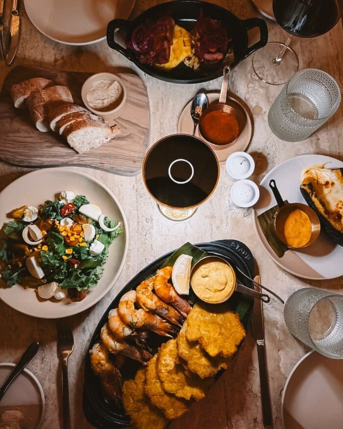 Overhead shot of dishes and wine at Tico Tica restaurant including salad, grilled shrimp and plantain chips.