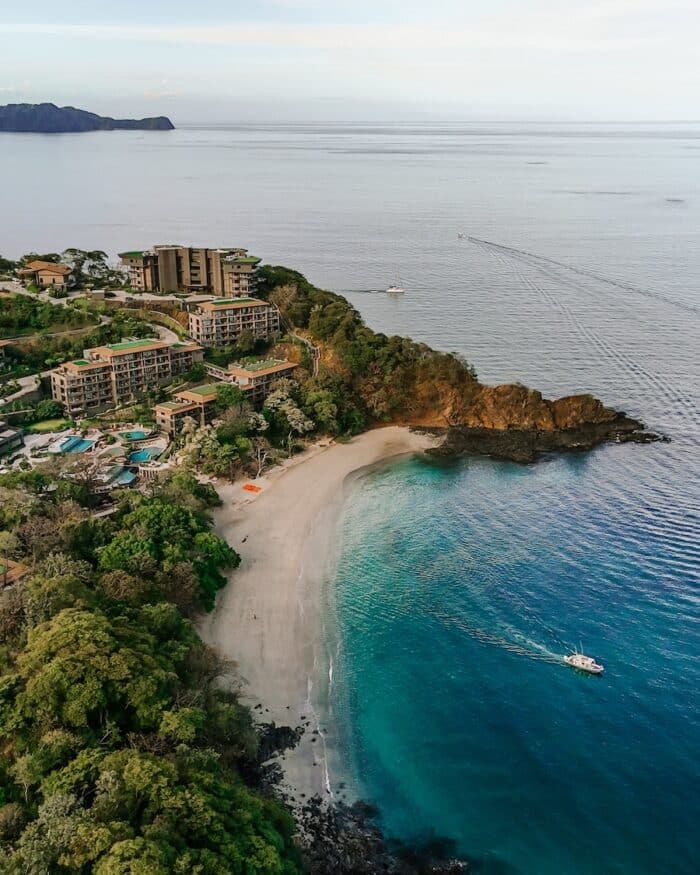 Drone shot of Waldorf Astoria Costa Rica with boat making waves in the bay