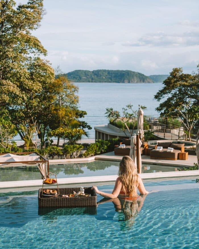 Michelle Halpern standing in a pool with a floating breakfast looking out to the ocean