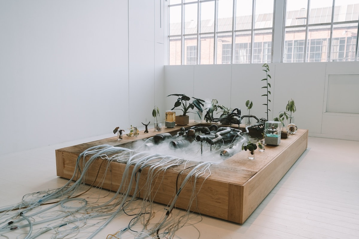 Modert art exhibition Modert art exhibition featuring metal piping and plans coming out of a steaming wooden slab