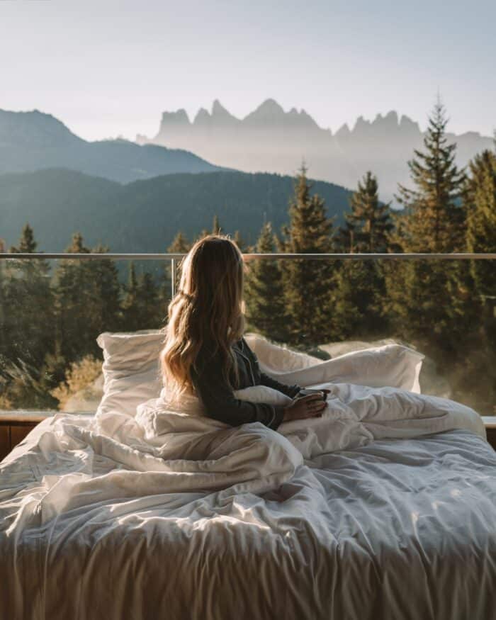 balcony of Forestis hotel Michelle Halpern laying holding a mug in a bed that's on the balcony of Forestis hotel