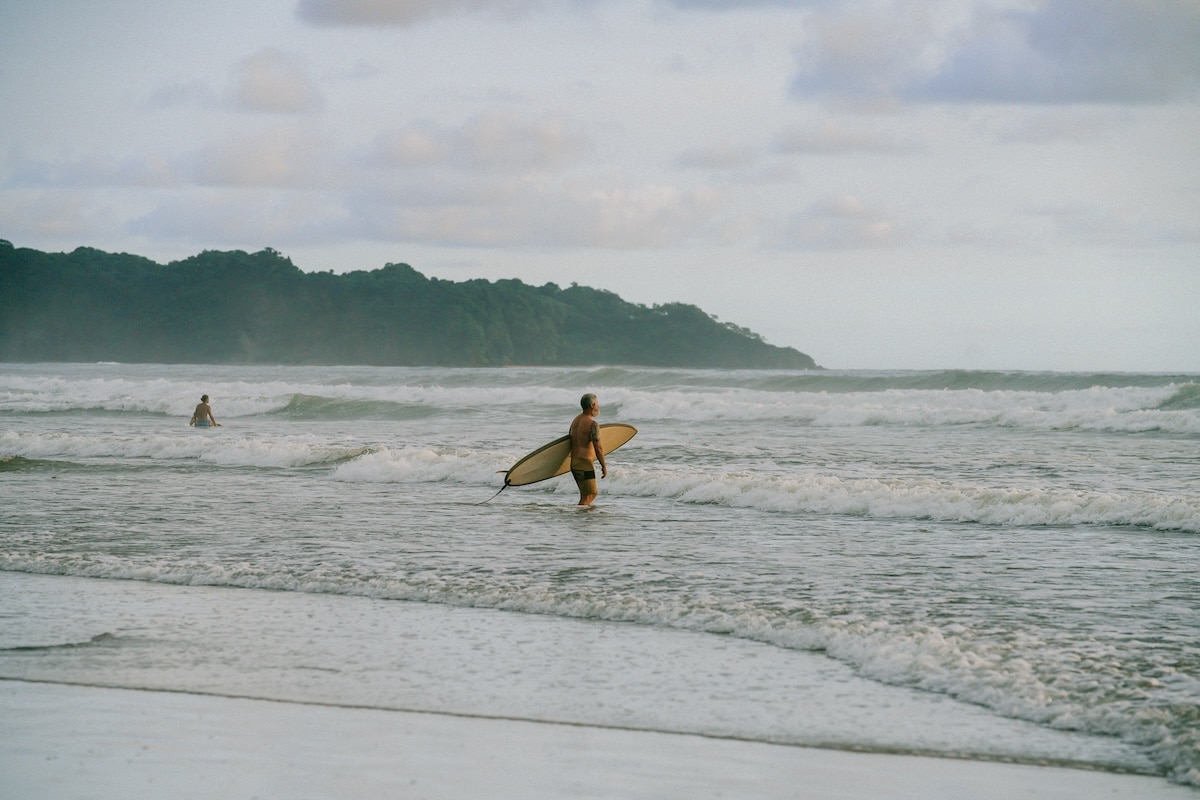 surfer Playa Guiones Surfer heading out into the waves on Playa Guiones carrying a yellow surfboard