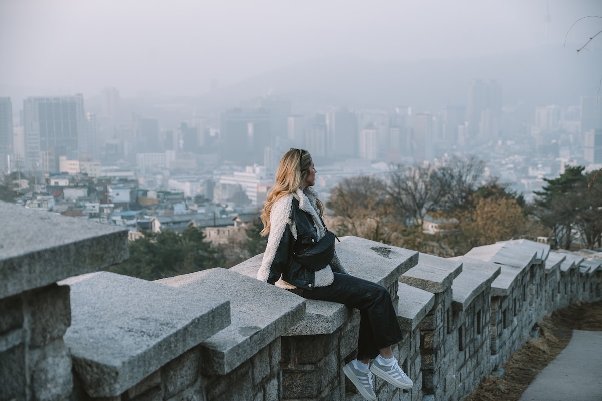 stone wall Seoul Michelle Halpern sitting on a stone wall that looks out over the Seoul skyline