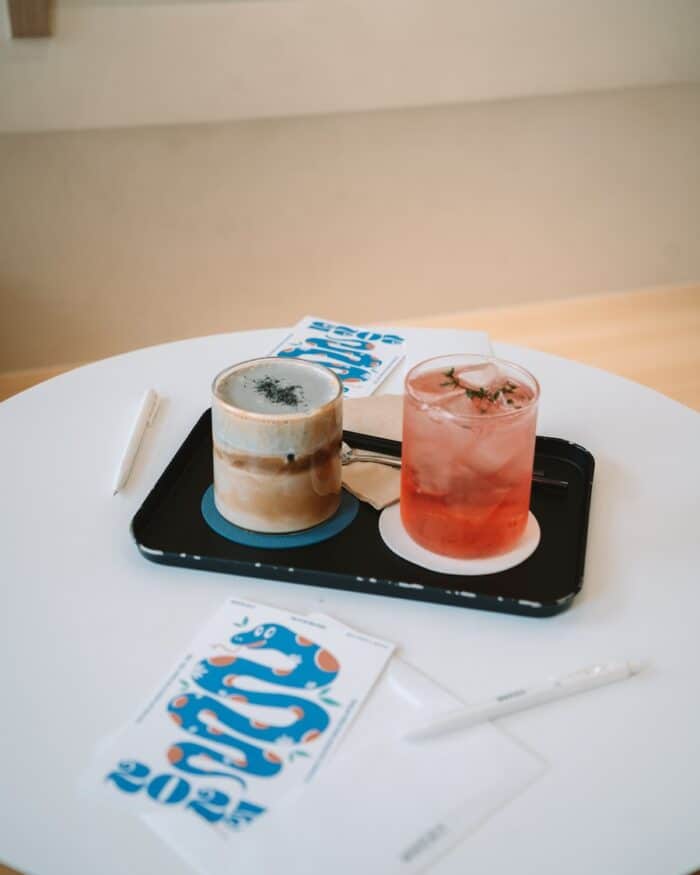 Nuldam Space Two drinks on a table with cards on the table that have a blue snake emblem on them
