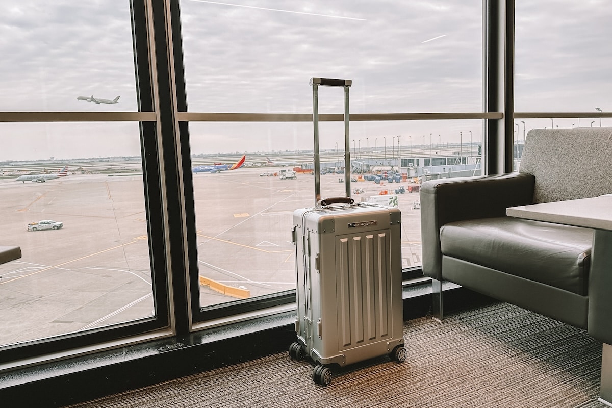 Silver hard case luggage Silver hard case luggage sitting by a window in the airport terminal