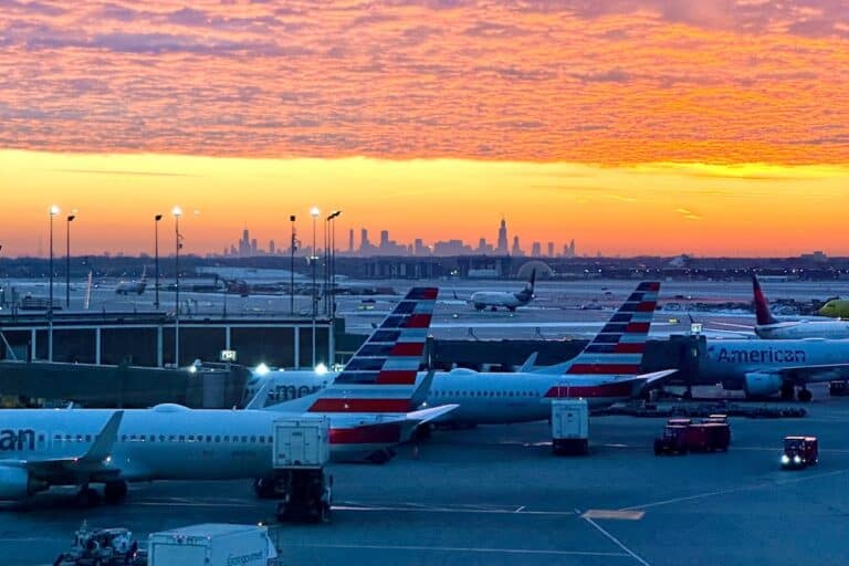Bright orange sunset view from airport with skyline in the distance and planes lined up in the foreground