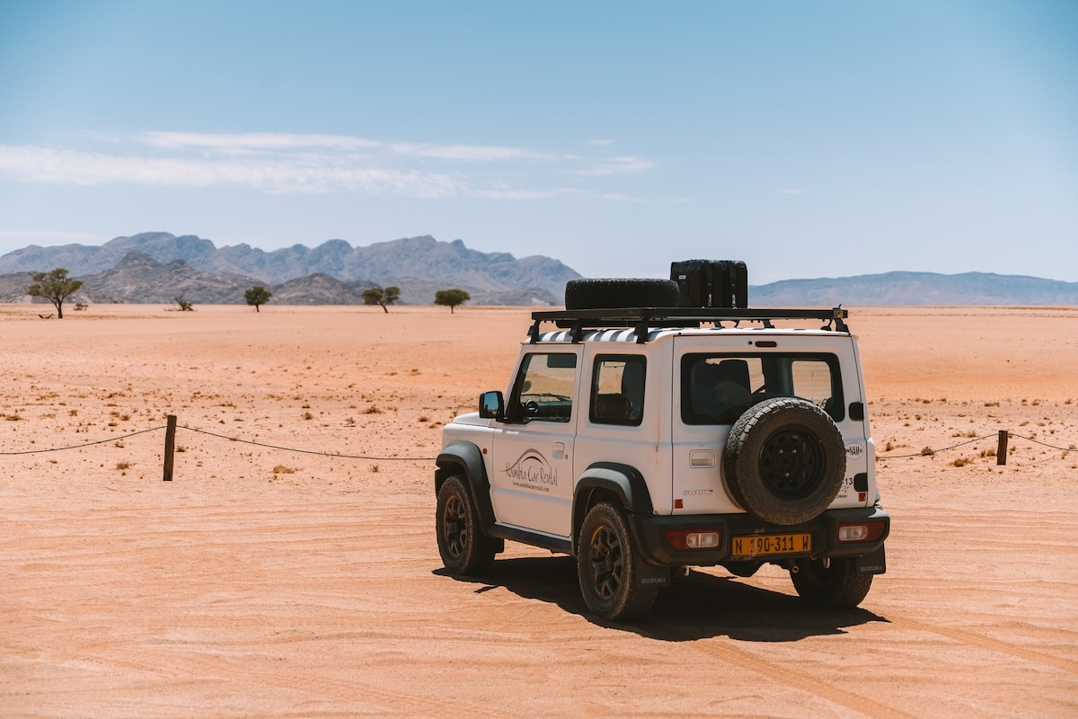 White Suzuki Jimny White Suzuki Jimny parked in front of barren sandy landscape in Namibia