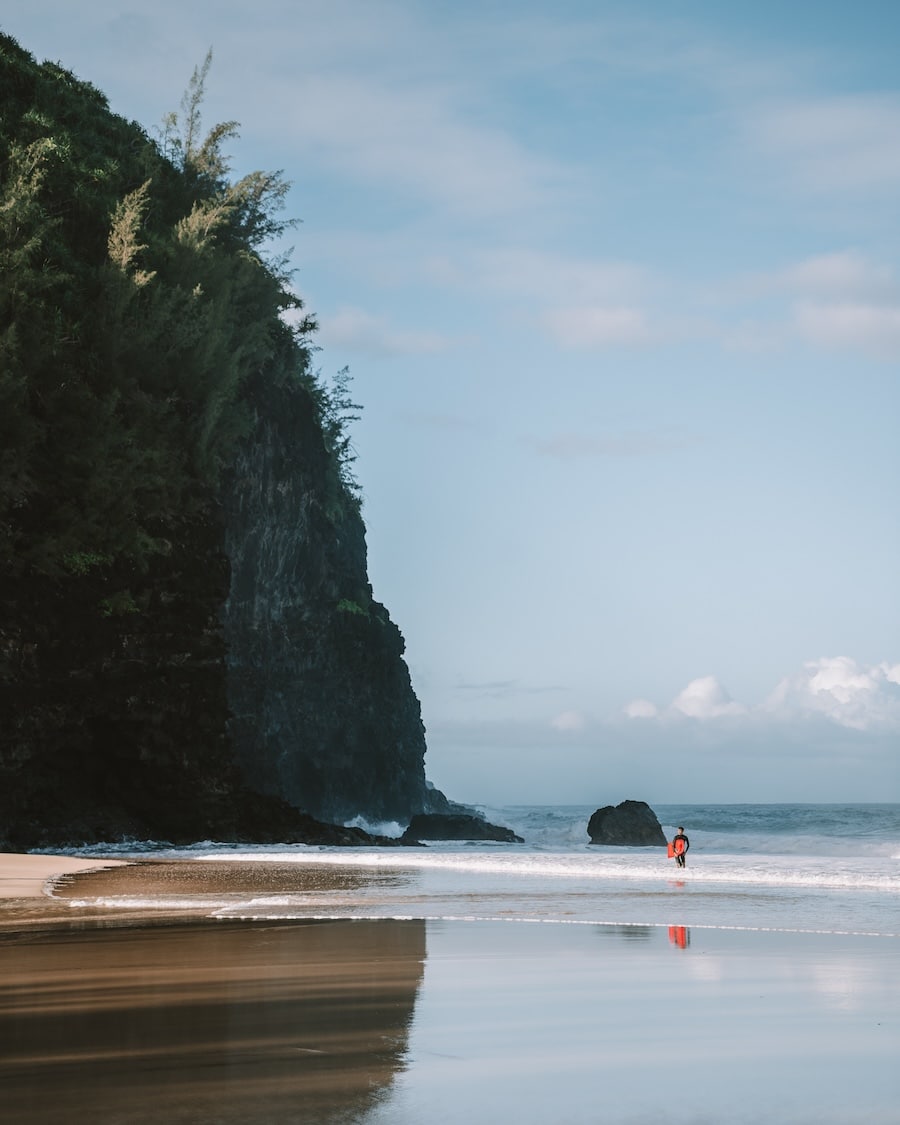 Surfer with red board Surfer with red board walking out of the waves at Hanakāpīʻai Beach