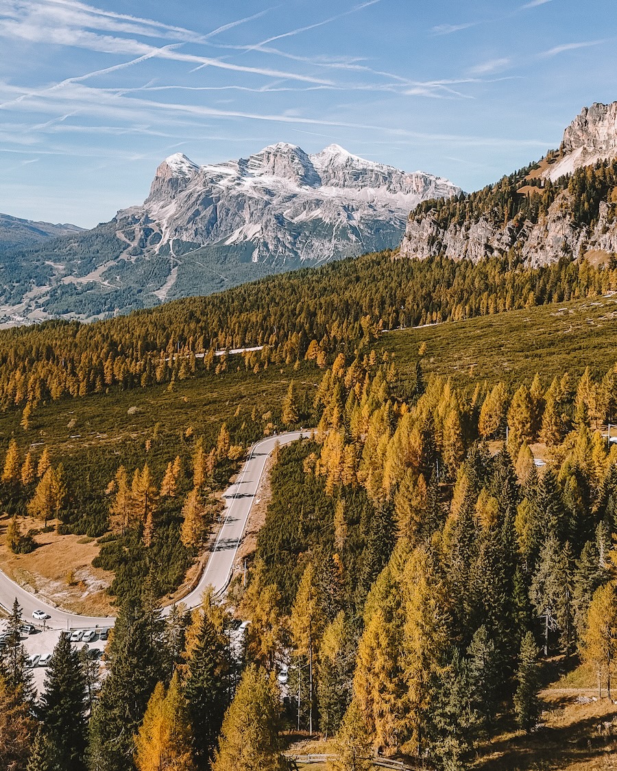 forest autumn Dolomites peaks Road winding through forest in autumn with Dolomites peaks in background