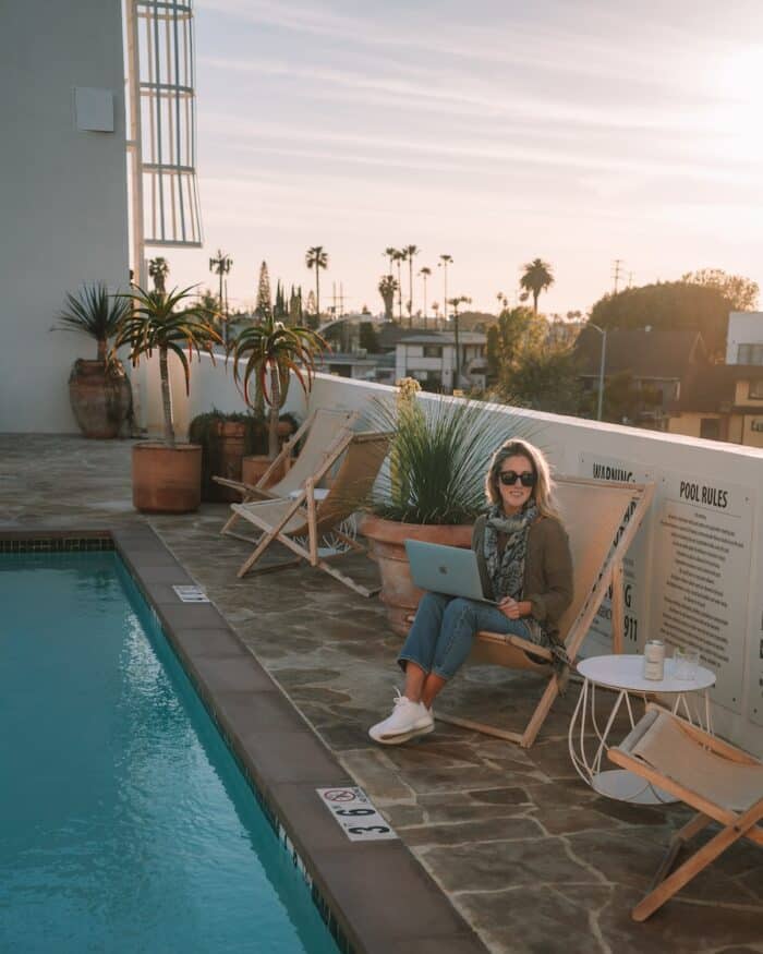 Packing List for International Travel Michelle sitting next to a pool with a laptop on her lap