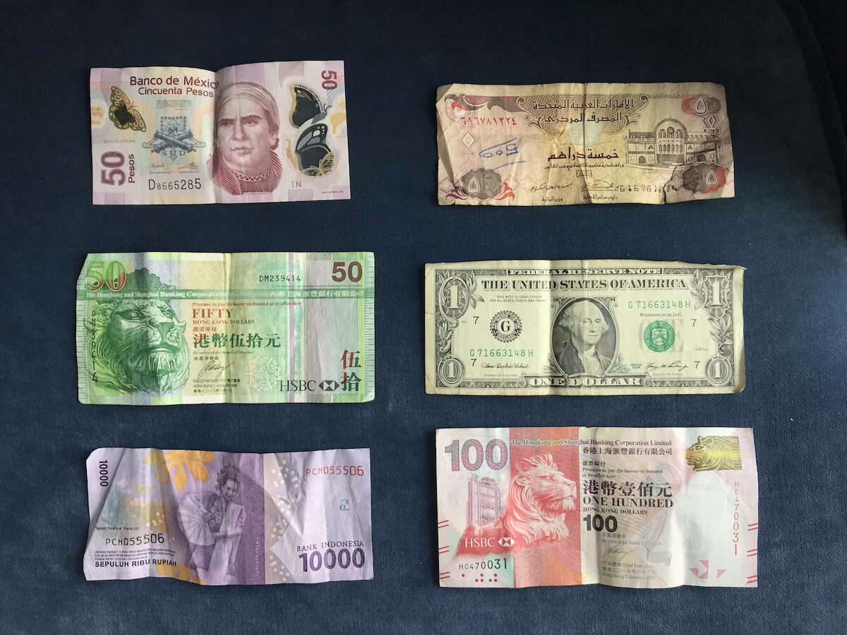 Packing List for International Travel six different currency bills on a dark background | Packing List for International Travel