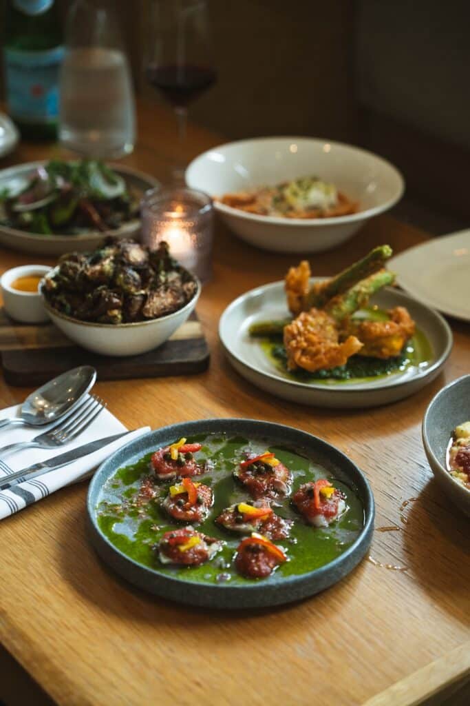 Cucina Urbana in San Diego Table full of dishes at Cucina Urbana in San Diego. On the table is hamachi crudo, squash blossoms and brussel sprouts.
