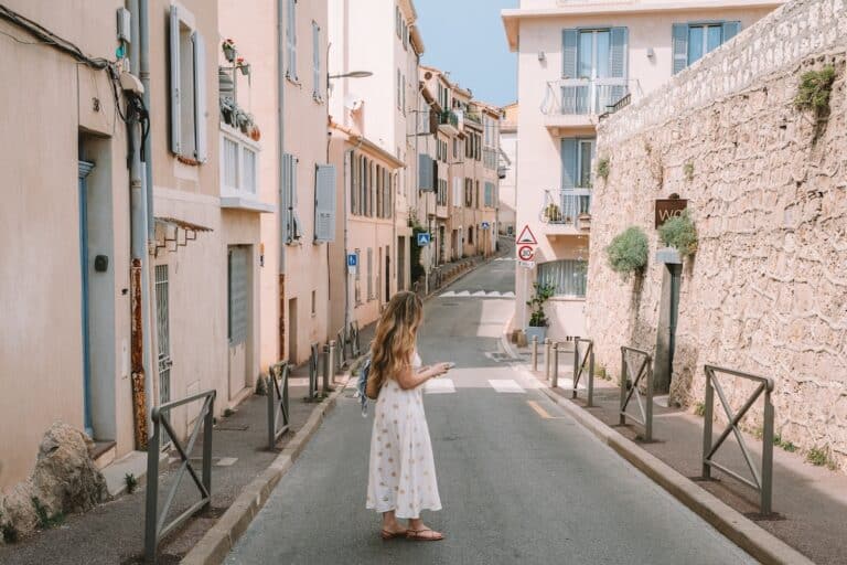 Michelle Halpern standing holding iphone in a charming street in Antibes, France