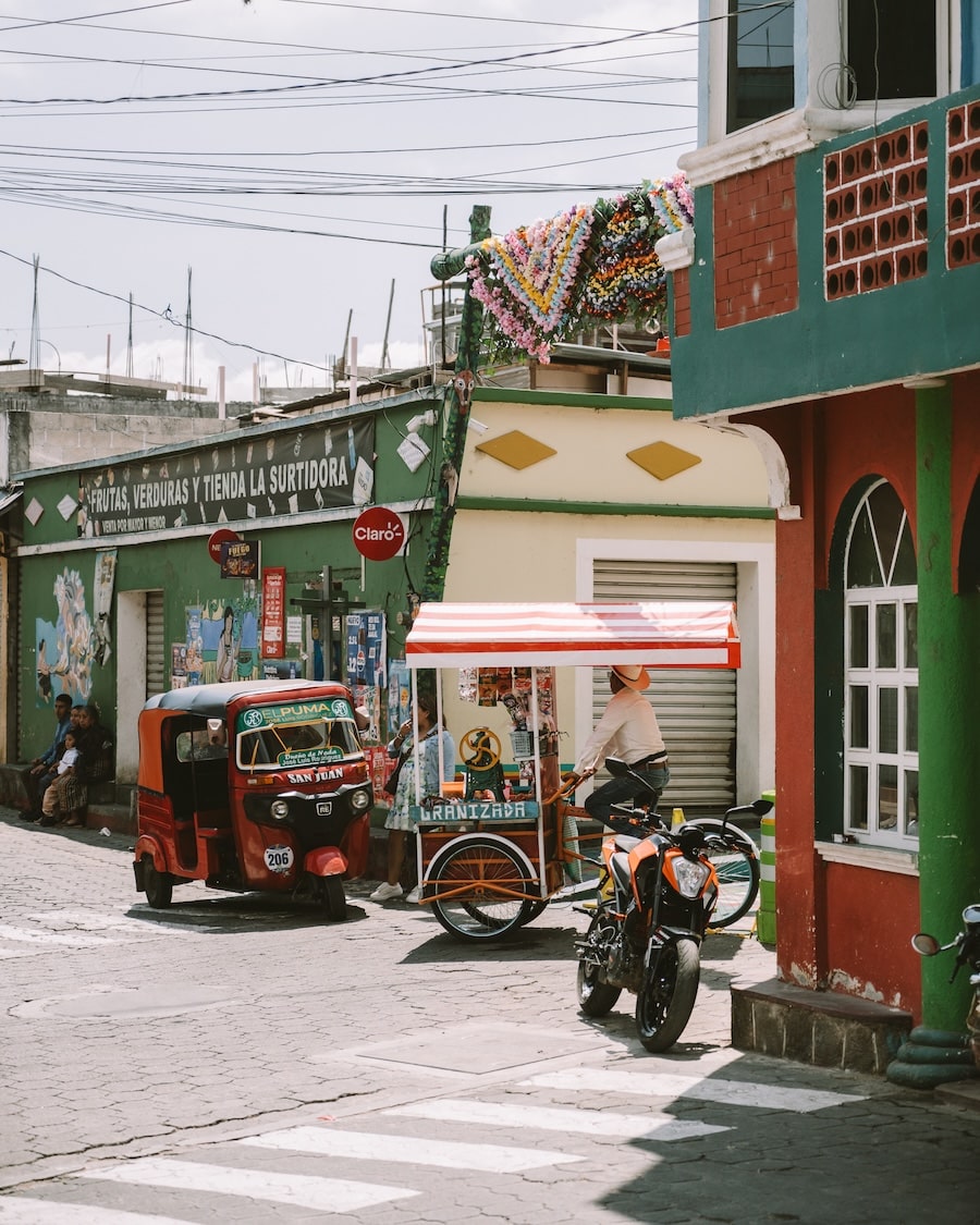 Street scene in San Juan La Laguna Street scene in San Juan La Laguna filled with colorful buildings, a tuk tuk, motorbike and street vendor