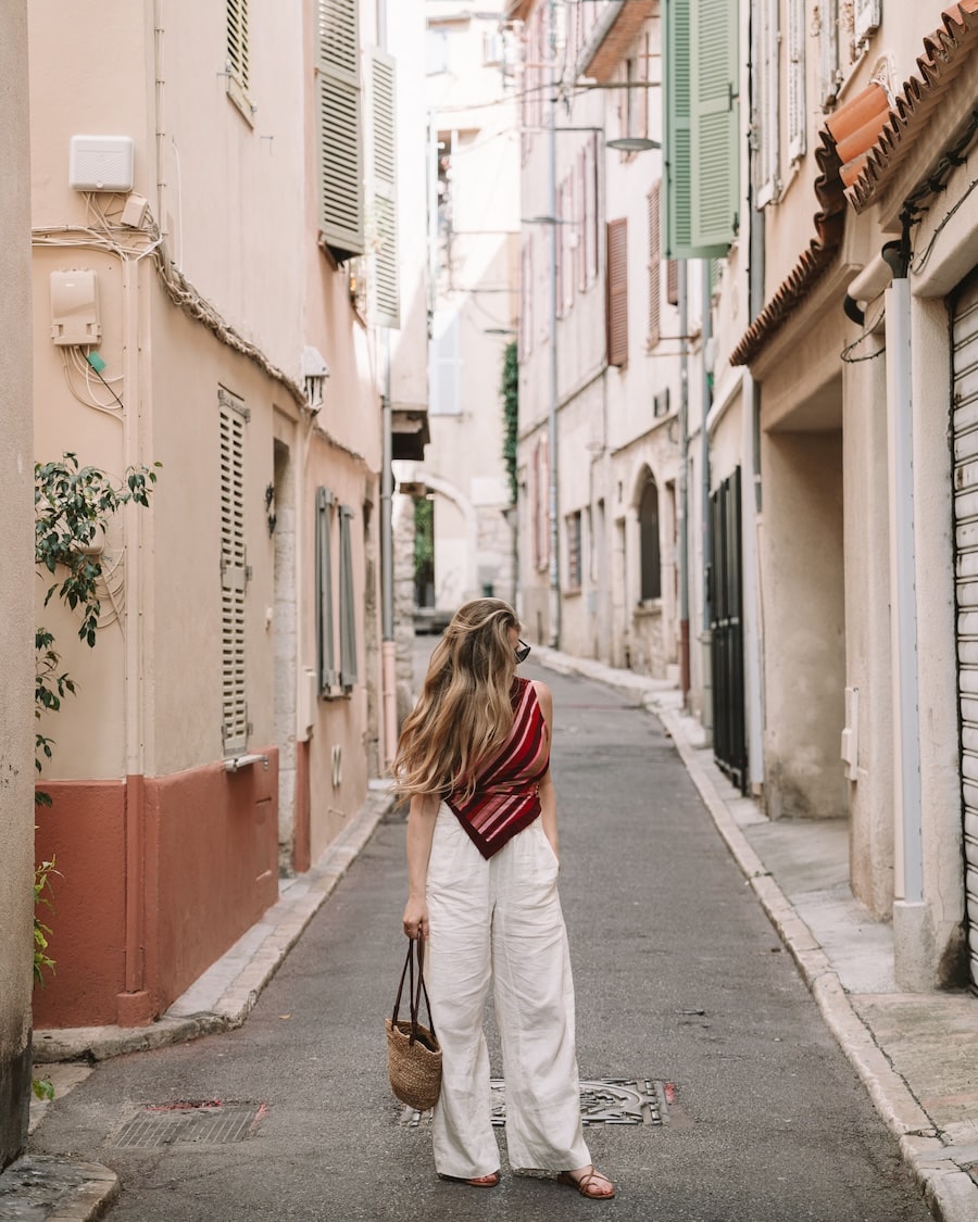 quaint street in Antibes Michelle Halpern wearing white pants and a red striped shirt on a quaint street in Antibes