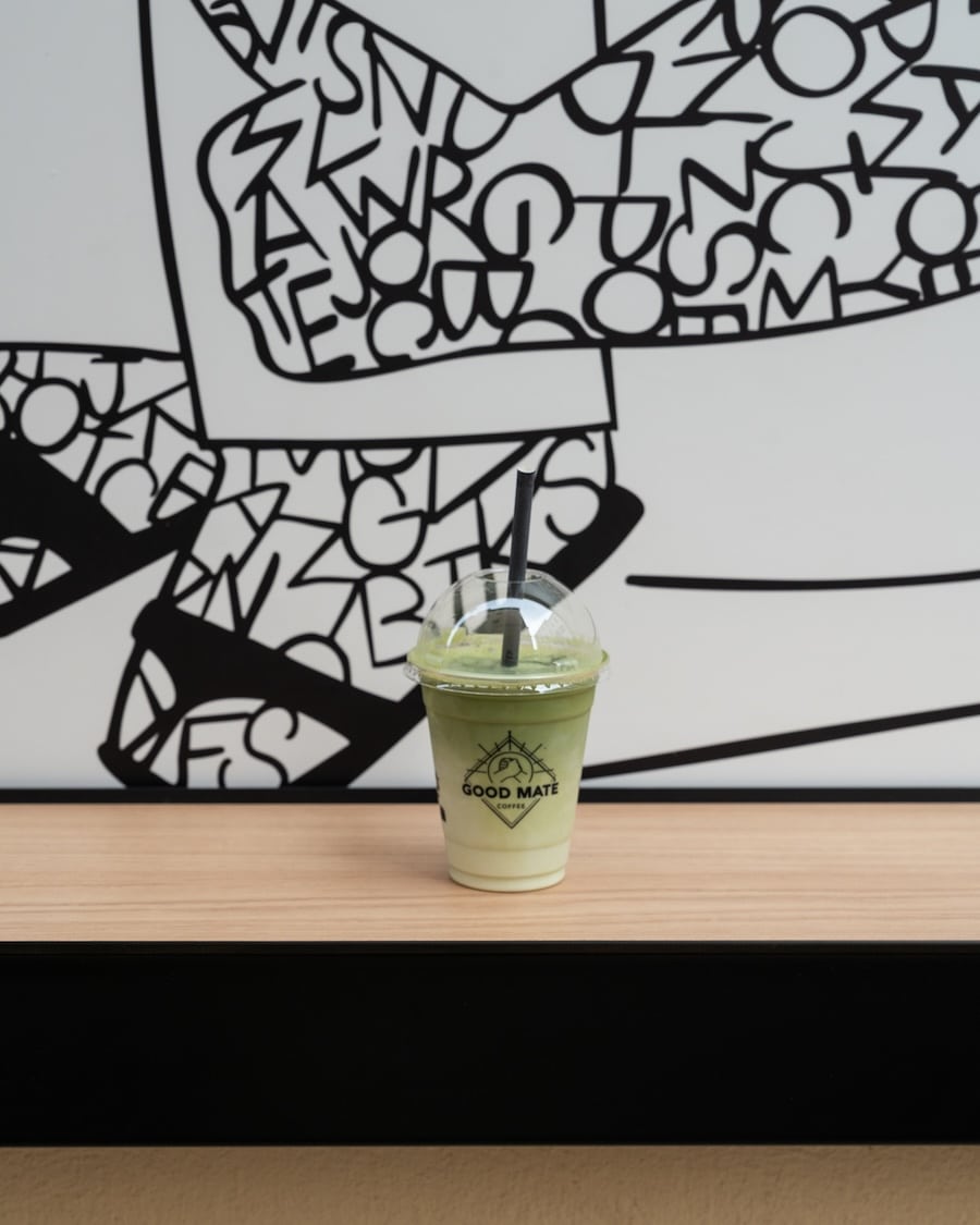 iced matcha Cup of iced matcha sitting on a wooden ledge with black and white artwork behind it