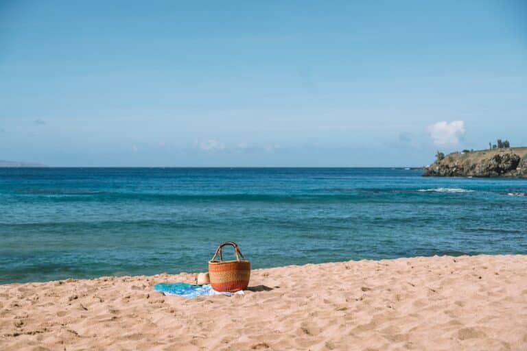 Wicker beach tote and a lone towel sitting on the sand at a deserted beach