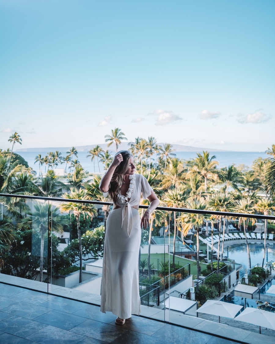 hotel balcony in Hawaii Michelle Halpern in a white long dress and a white lei looking out over a hotel balcony in Hawaii | What To Pack For A Beach Vacation