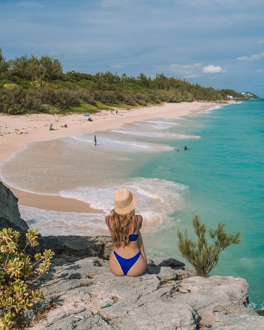 rock in Bermuda Michelle Halpern sitting on a rock in Bermuda that looks out to turquoise water | What To Pack For A Beach Vacation