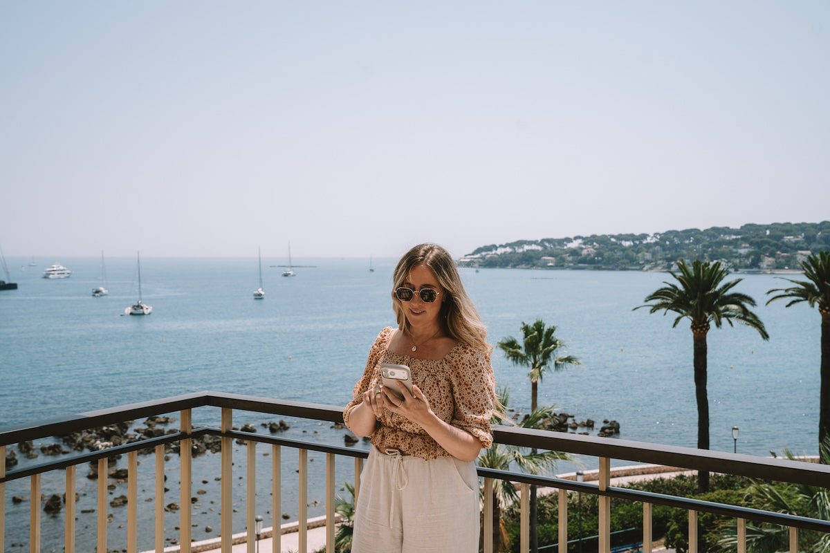 balcony in Antibes Michelle Halpern standing on a balcony in Antibes that overlooks the water, doing something on her iPhone